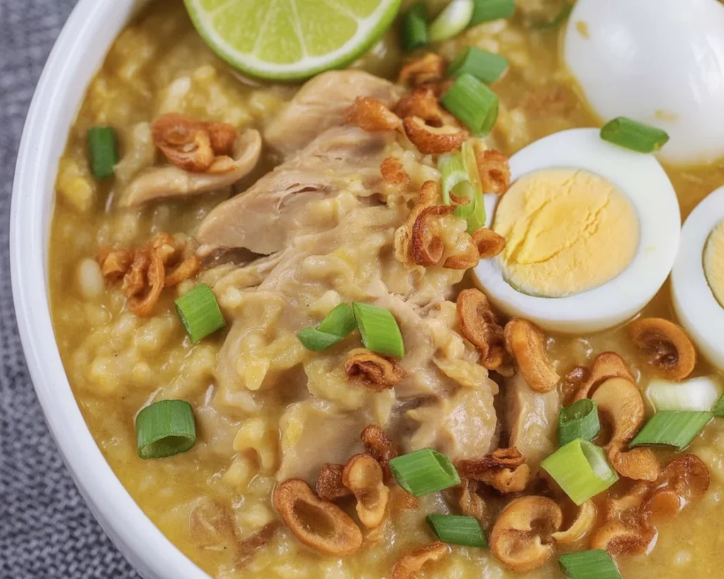 Bowl of Filipino chicken arroz caldo topped with hard-boiled eggs and scallions.