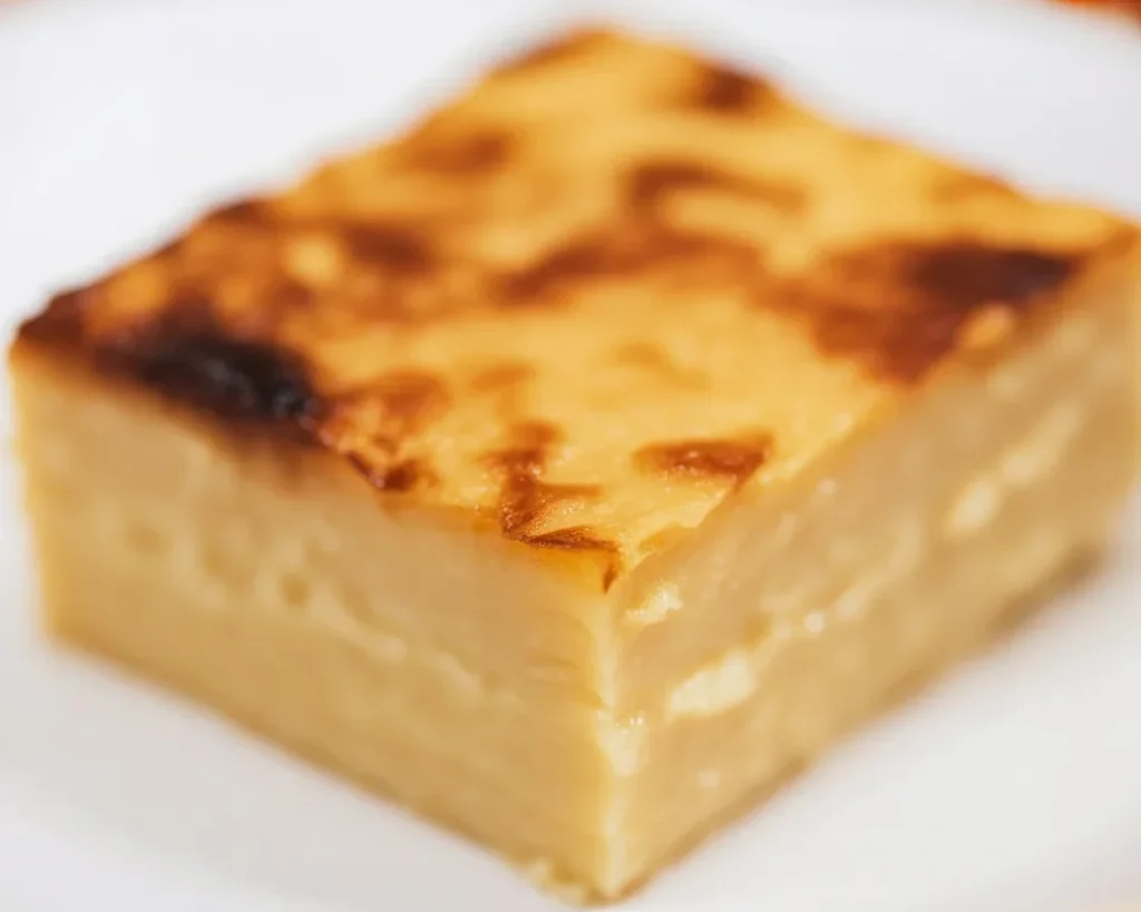 Delicious Filipino Cassava Cake topped with custard and served in a traditional setting.
