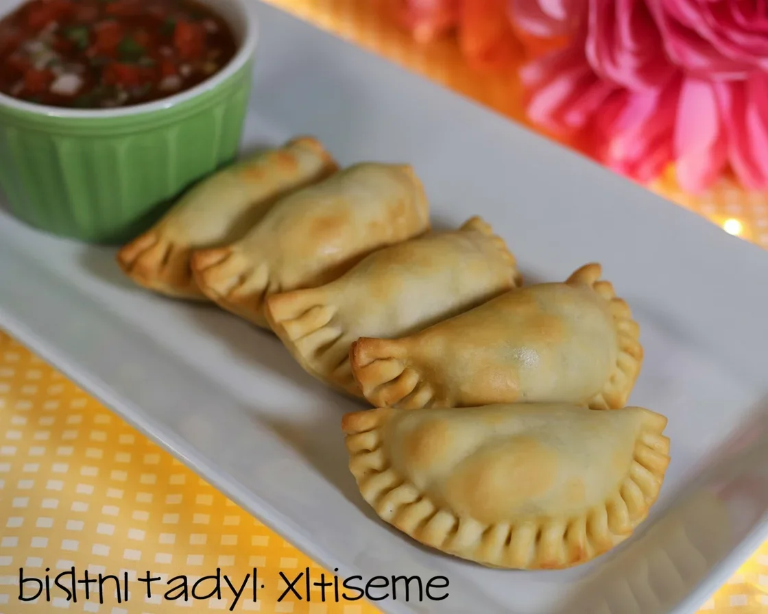 Plate of chicken empanadas served with dipping sauce, perfect appetizer for any occasion.