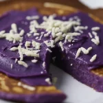 Fluffy ube pancakes topped with ube coconut sauce and toasted coconut flakes