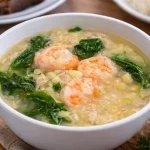 A bowl of creamy Filipino corn soup garnished with herbs.